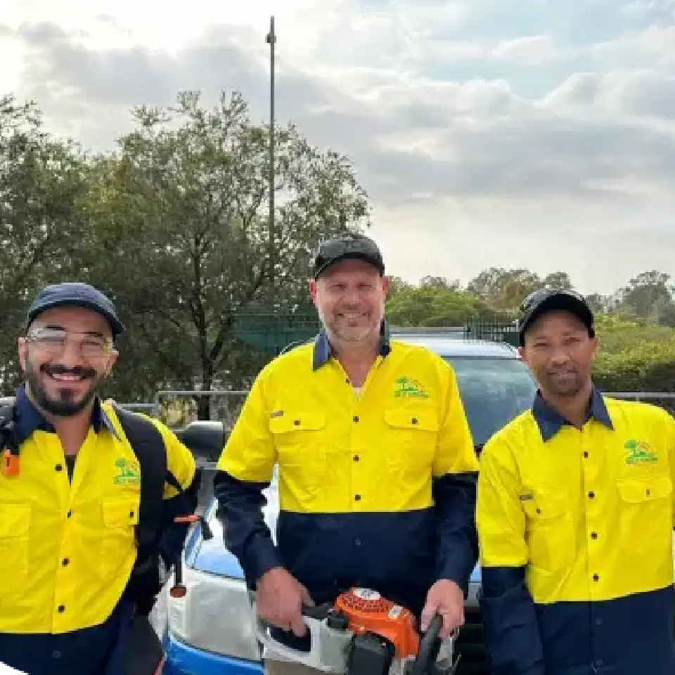 Oxley Gardening & Property Maintenance workers planting a tree and preparing soil beside a fence during a landscaping project.