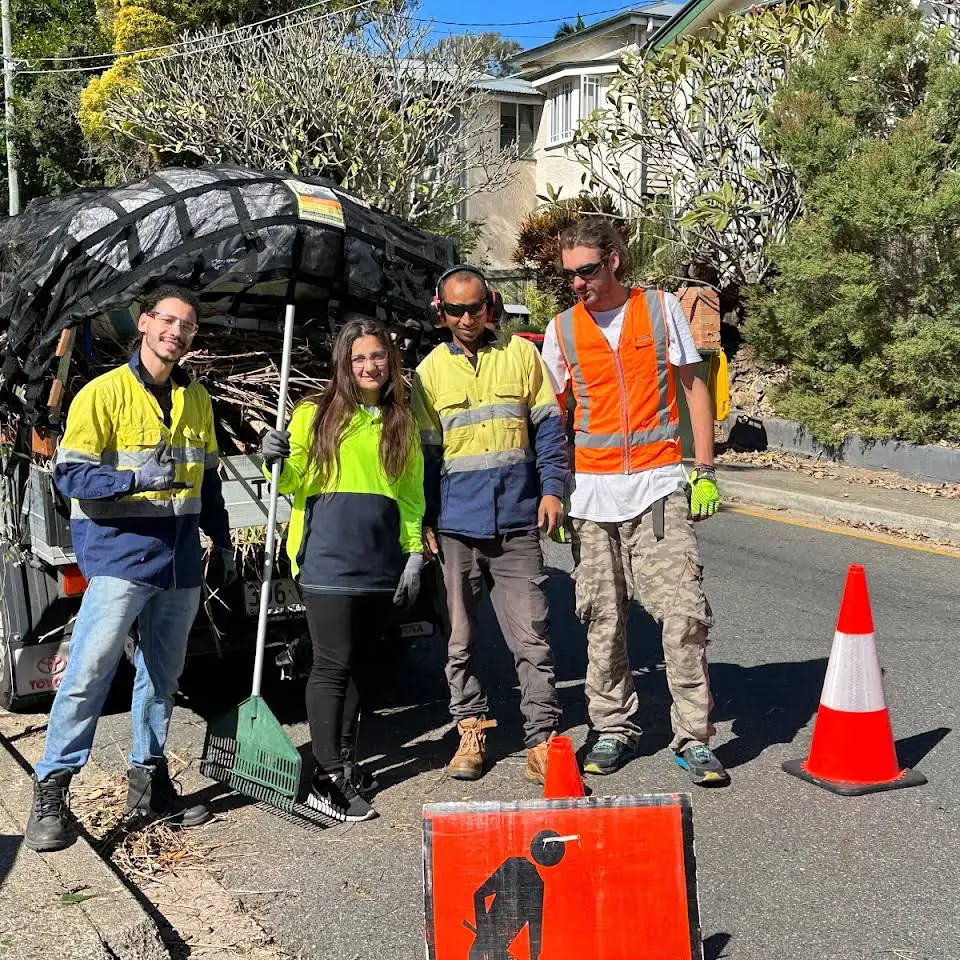 Oxley GPM crew posing with safety gear and tools after completing a green waste removal job in a suburban Brisbane street.